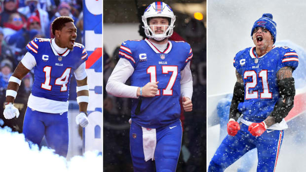 Stefon Diggs yells with his fists pushing down by his sides as smoke comes up around his legs; Josh Allen jogs onto the field; Jordan Poyer yells in celebration with his arms clenching downward